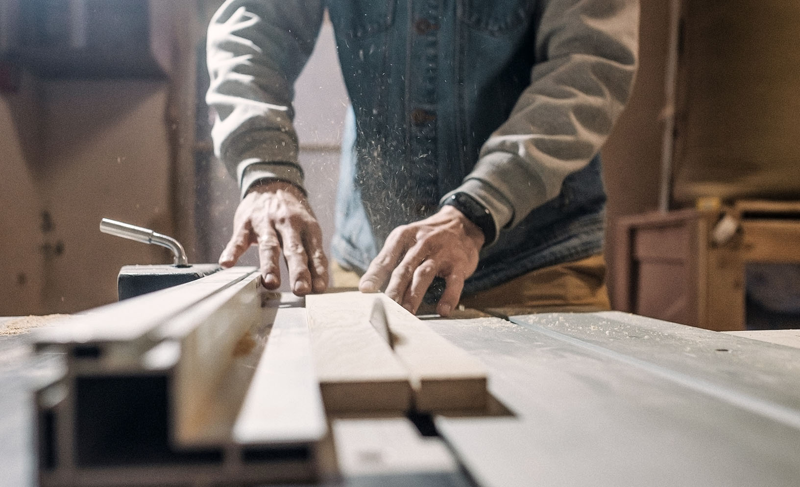 Electric saw cutting wood board. Man working at carpentry workshop